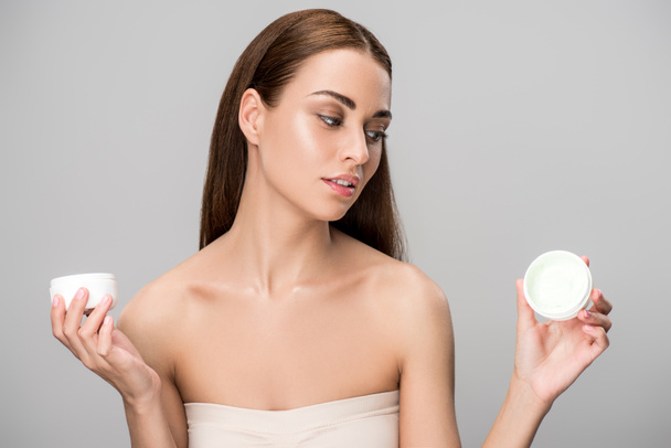 attractive girl choosing face cream, isolated on grey - Фото, зображення