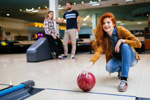 Beautiful woman bowling with friends getting ready to throw ball - Foto, Imagem