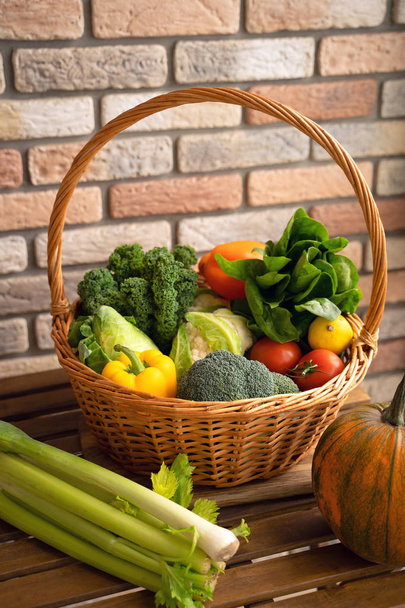 Gezonde verse groenten en fruit in wilgen mand op houten achtergrond - Foto, afbeelding