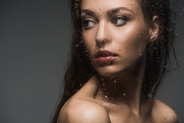 young woman behind wet glass, isolated on grey - Valokuva, kuva