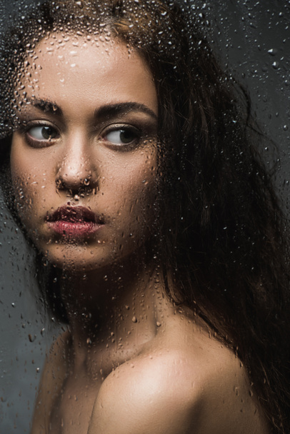 attractive brunette woman behind wet glass in shower - Foto, Bild