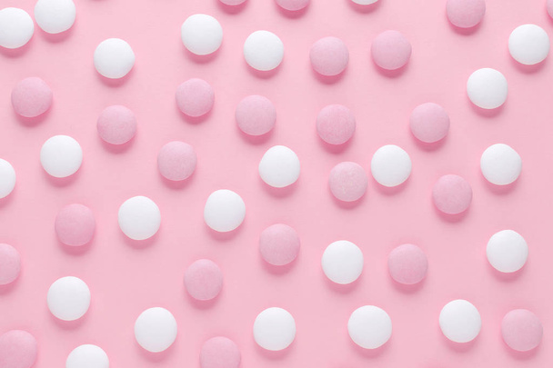абстрактний візерунок з рожевих і білих цукерок або таблеток на пастельному кольоровому фоні
 - Фото, зображення