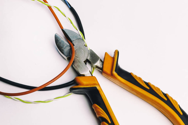 Cutting cable with nippers, on a white background, no isolated, there is toning, close-up - Φωτογραφία, εικόνα