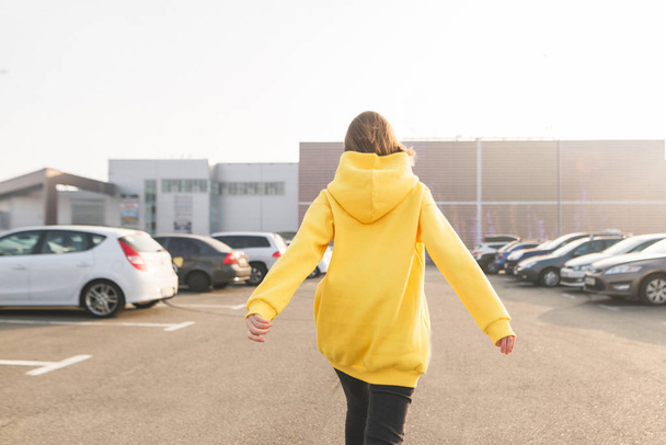Kız içeri sarı hoodie cadde boyunca yürüyüş. Lookbook. Sokak moda portre - Fotoğraf, Görsel