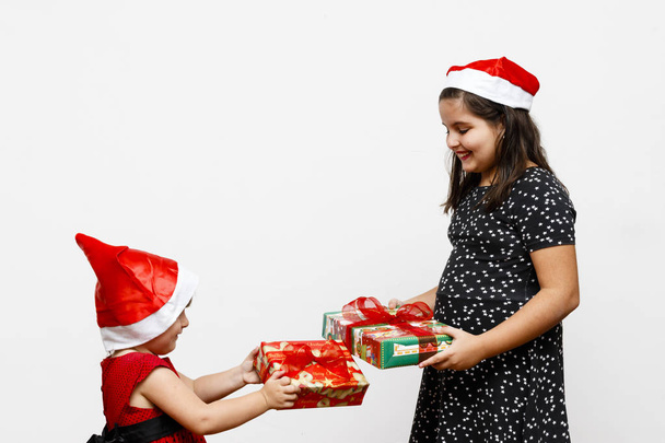 two girls sisters exchanging christmas gifts, white background - Foto, afbeelding
