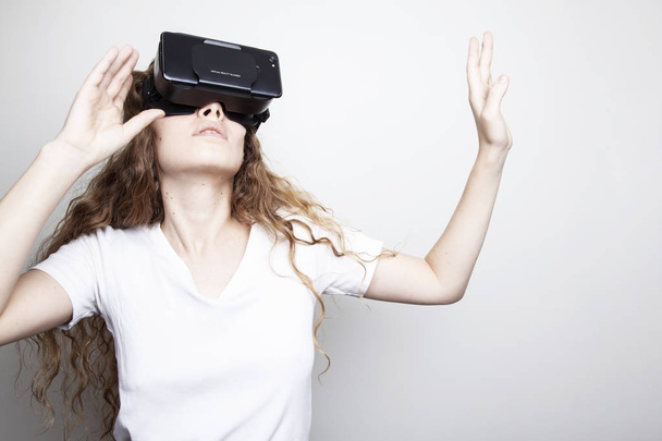 beautiful young woman in vr headset standing in front of white wall - Photo, Image