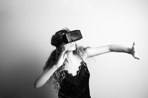 black and white shot of beautiful young woman in vr headset standing in front of white wall - Photo, Image