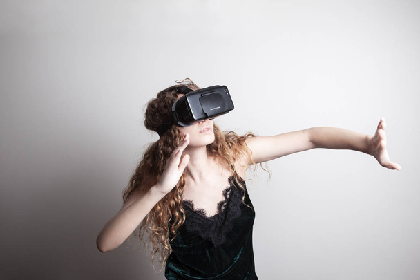 beautiful young woman in vr headset standing in front of white wall - Photo, Image