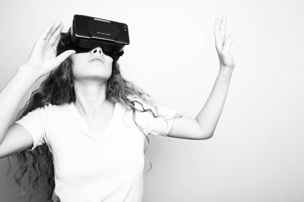 black and white shot of beautiful young woman in vr headset standing in front of white wall - Photo, Image