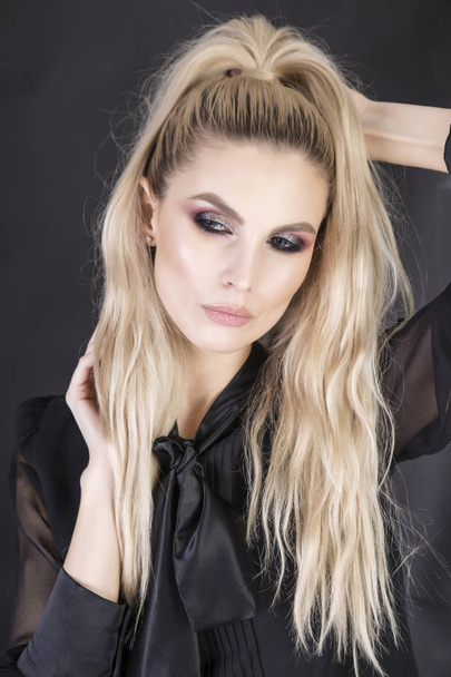 Long messy hairstyle and strong professional make up on beautiful blonde model. - Foto, afbeelding