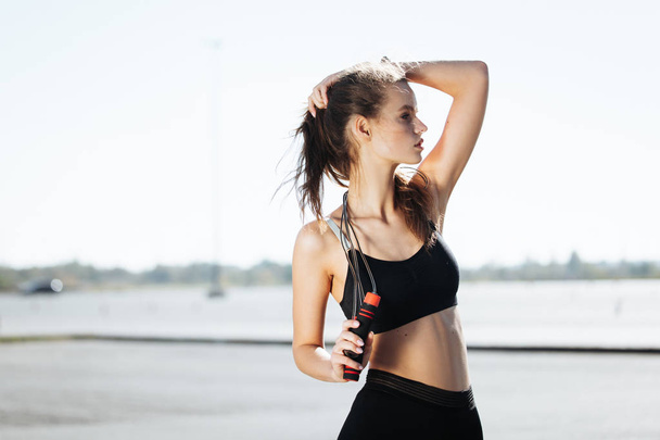 Tired fitness woman wipes sweat from forehead, feels fatigue after active cardio workout, does fitness exercise, has serious expression into distance - 写真・画像