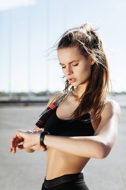 atletische meisje kijkt naar een fitness-armband - Foto, afbeelding