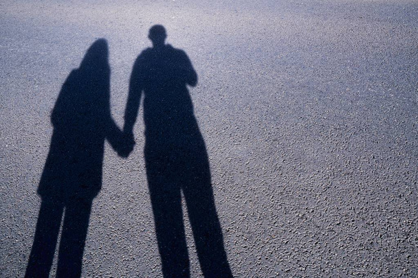 Silhueta de um casal amor em lançar mão na mão amor em uma longa sombra na rua.Sombras de pedestres andando projetadas na calçada. Foto artística em preto e branco, B & W no dia ensolarado
. - Foto, Imagem