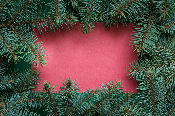 赤の背景に evegreen の枝とクリスマスの国境。メリー クリスマスのグリーティング カード、バナー、フレーム。冬の休日のテーマ。明けましておめでとう。願いのためのスペース. - 写真・画像