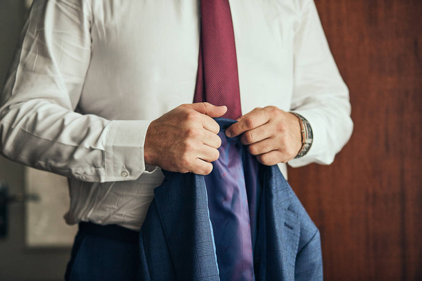 Businessman wears a jacket,male hands closeup,groom getting ready in the morning before wedding ceremony - Фото, изображение