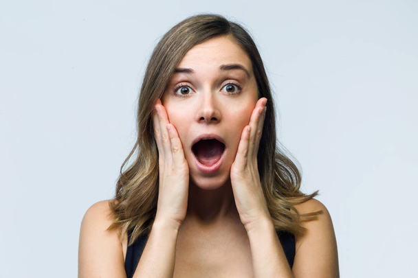 Portrait of surprised young woman screaming and putting her hands on her face looking at camera isolated on white. - Foto, imagen