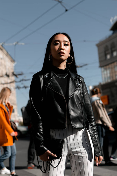 Street stylish portrait of a girl of Asian appearance on the streets of the city on a sunny day - Fotó, kép