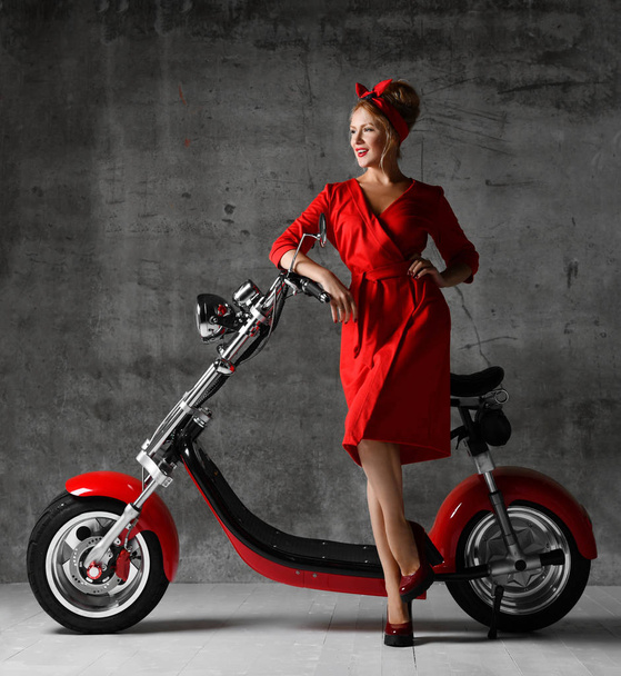 Woman ride sit on motorcycle bicycle scooter pinup retro style looking down in red blouse and jeans - Фото, зображення