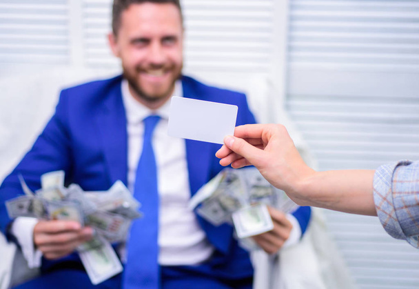 Smiling businessman with bundle of american dollar cash money at office. Pay card. Business, people, success and fortune concept. - Фото, изображение
