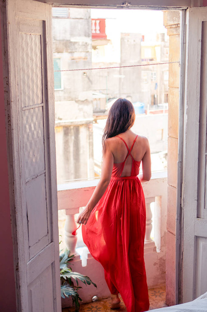 Young attractive woman in red dress on old balcony in apartments in Havana, Cuba - Photo, Image