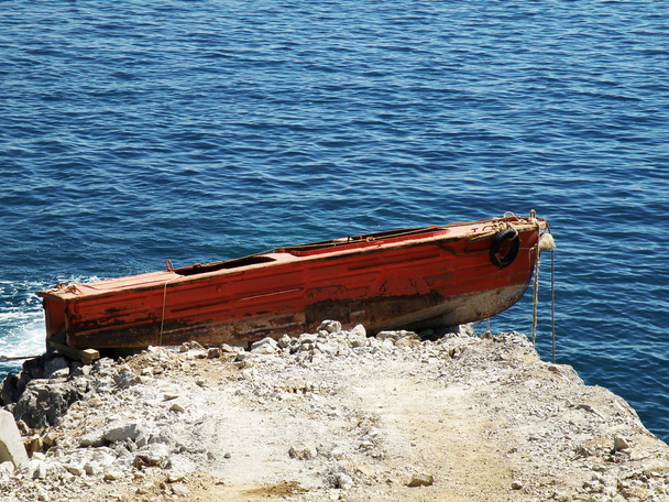 Barco rojo viejo varado en rocas
 - Foto, Imagen