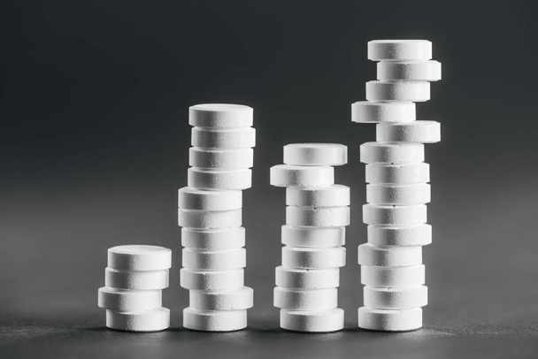 close up view of stacks of white pills placed in rows on grey - 写真・画像