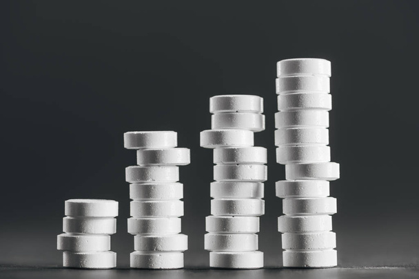 vista de cerca de pilas dispuestas de píldoras blancas colocadas en filas en gris
 - Foto, imagen