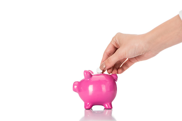 cropped image of woman putting pill into pink piggy bank isolated on white - Foto, imagen