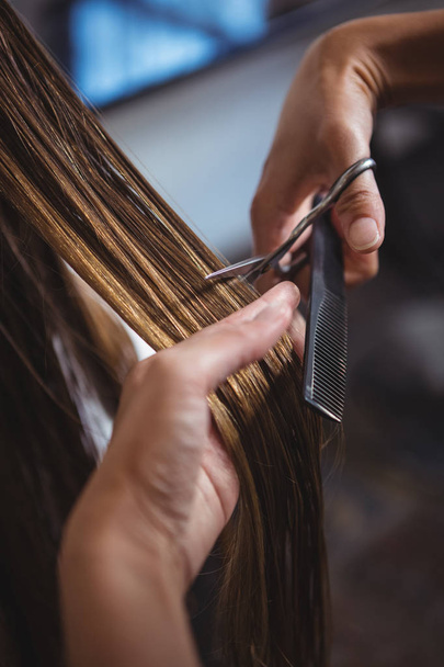 abgeschnittenes Bild einer Frau, die sich im Salon die Haare schneiden lässt - Foto, Bild