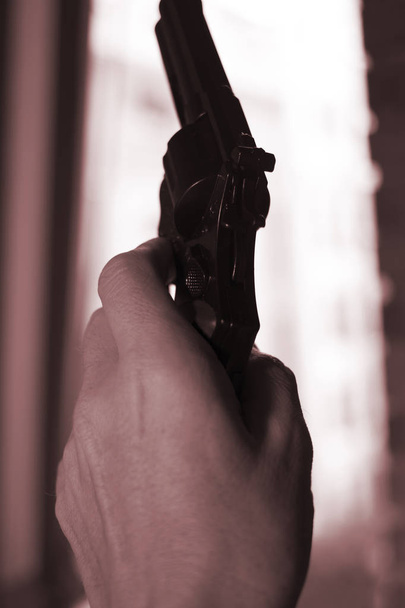 Pistol automatic handgun weapon in silhouette in hand of killer atmospheric dark dramatic photo. - Fotó, kép