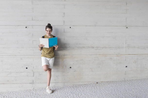 estudiante con mochila y libros en la pared de fondo
 - Foto, Imagen