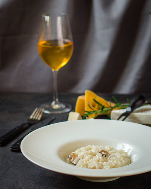 risotto aux moules (riz aux fruits de mer) dans une assiette blanche et un verre de vin blanc sur fond sombre
 - Photo, image