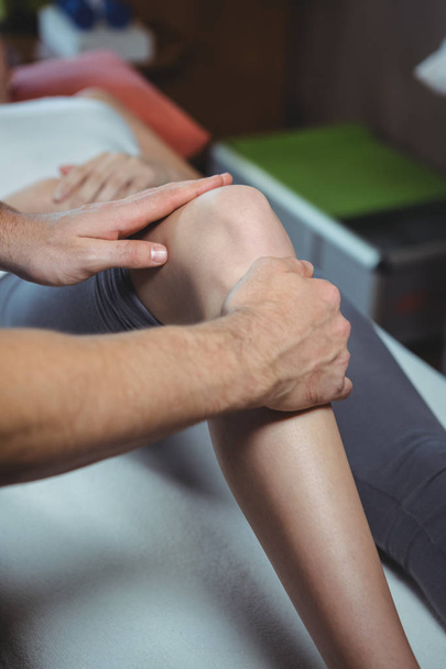 обрезанный образ физиотерапевта, проводящего физиотерапию колена пациентки в клинике
 - Фото, изображение