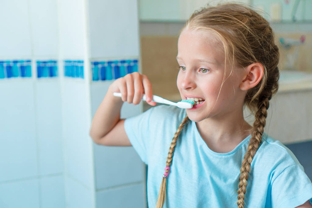 Schattig meisje borstels tanden in de badkamer. - Foto, afbeelding