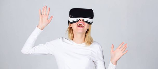Portrait of an amazed girl using a virtual reality headset isolated on grey background. Happy woman exploring augmented world, interacting with digital interface. Virtual reality headsets - Foto, Imagem