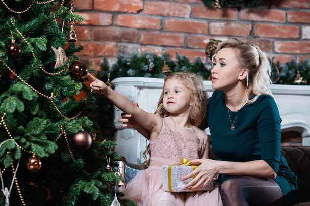 Beautiful Mother and daughter decorate the Christmas tree. Merry Christmas and happy holidays. - Foto, afbeelding