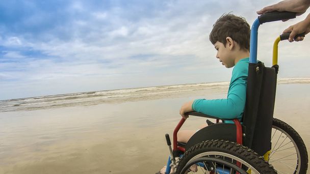 silla de ruedas infantil horizonte arena pie
 - Foto, imagen