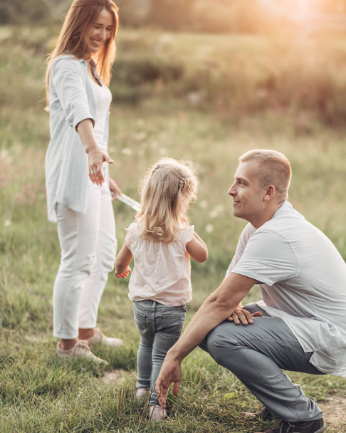 Young Adult Couple with Their Little Daughter Having Fun in the Park Outside the City, Family Weekend Picnic Concept, Three People Enjoying Summer - Foto, Imagem