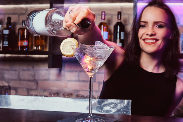 Una hermosa chica camarera prepara un cóctel alcohólico con vodka
 - Foto, Imagen