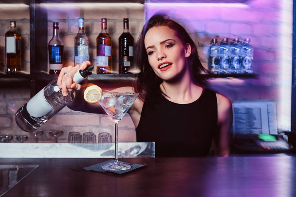A beautiful girl bartender prepares an alcoholic cocktail with vodka - Photo, image
