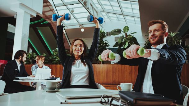 Corporate Sport Lifestyle. Healthcare of Business People. Office Workers Working with Dumbbells. Workers doing Fitness Exercises. Yoga Practice. Employee Man Smiling to Healthy Woman. - Photo, Image