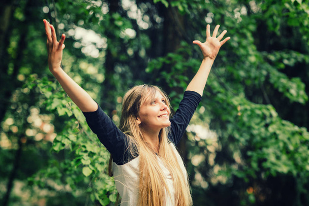 Lächelnde junge Frau beim Yoga mit erhobenen Händen - Foto, Bild