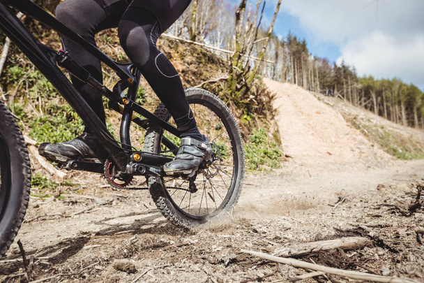 Low section of mountain biker riding on dirt road at mountain - Photo, Image