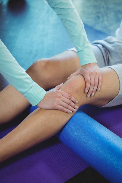 geschnittenes Bild einer Physiotherapeutin, die dem Knie eines männlichen Patienten in der Klinik physikalische Therapie gewährt - Foto, Bild