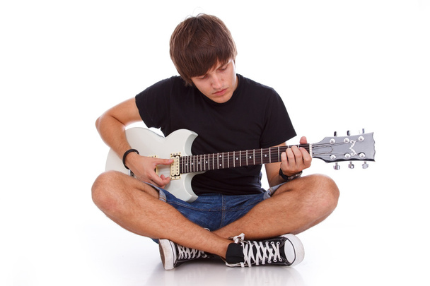 Teenage boy is sitting on the floor with crossed legs while play - Photo, image