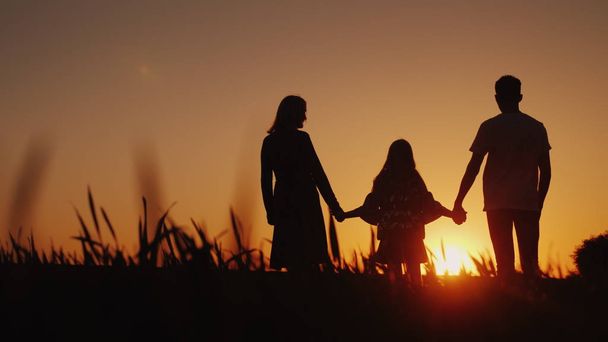 Rodiče s dítětem stojí na malebném místě, obdivovat východ slunce. Držení rukou. Šťastný rodinný koncept - Fotografie, Obrázek