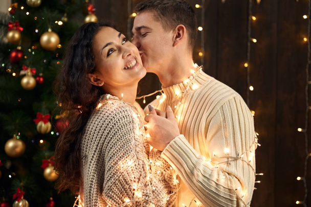 Genç bir çift olan Noel dekorasyonu ve ışıklar, köknar ağacı Yılbaşı tatil kavramı koyu ahşap arka plan üzerinde - Fotoğraf, Görsel
