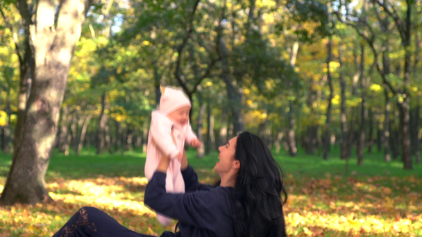 Glückliche Mutter wirft ihr Baby hoch im Park - Filmmaterial, Video