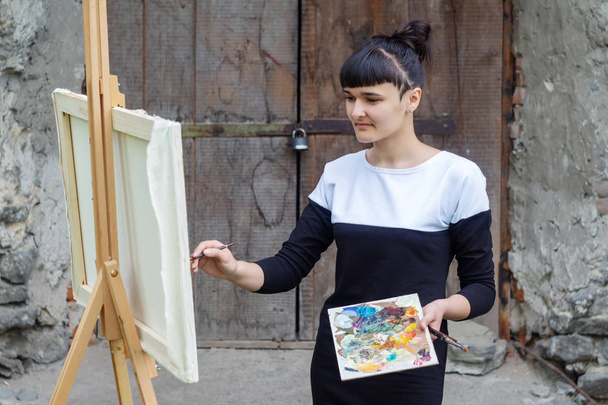 Artystka maluje obraz na podwórku. Kamieniec Podolski, Ukraina. - Zdjęcie, obraz