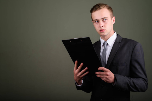 Jonge knappe zakenman dragen pak tegen gekleurde CHTERGRO - Foto, afbeelding